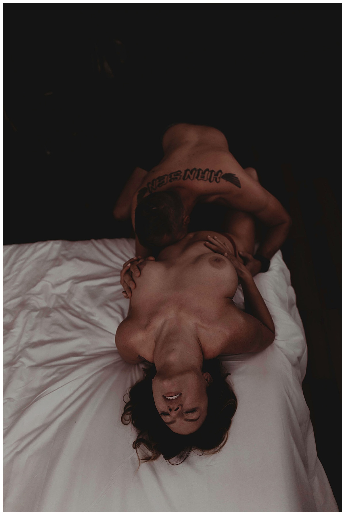 Husband and wife lay against edge of bed for Boudoir Photography Minneapolis