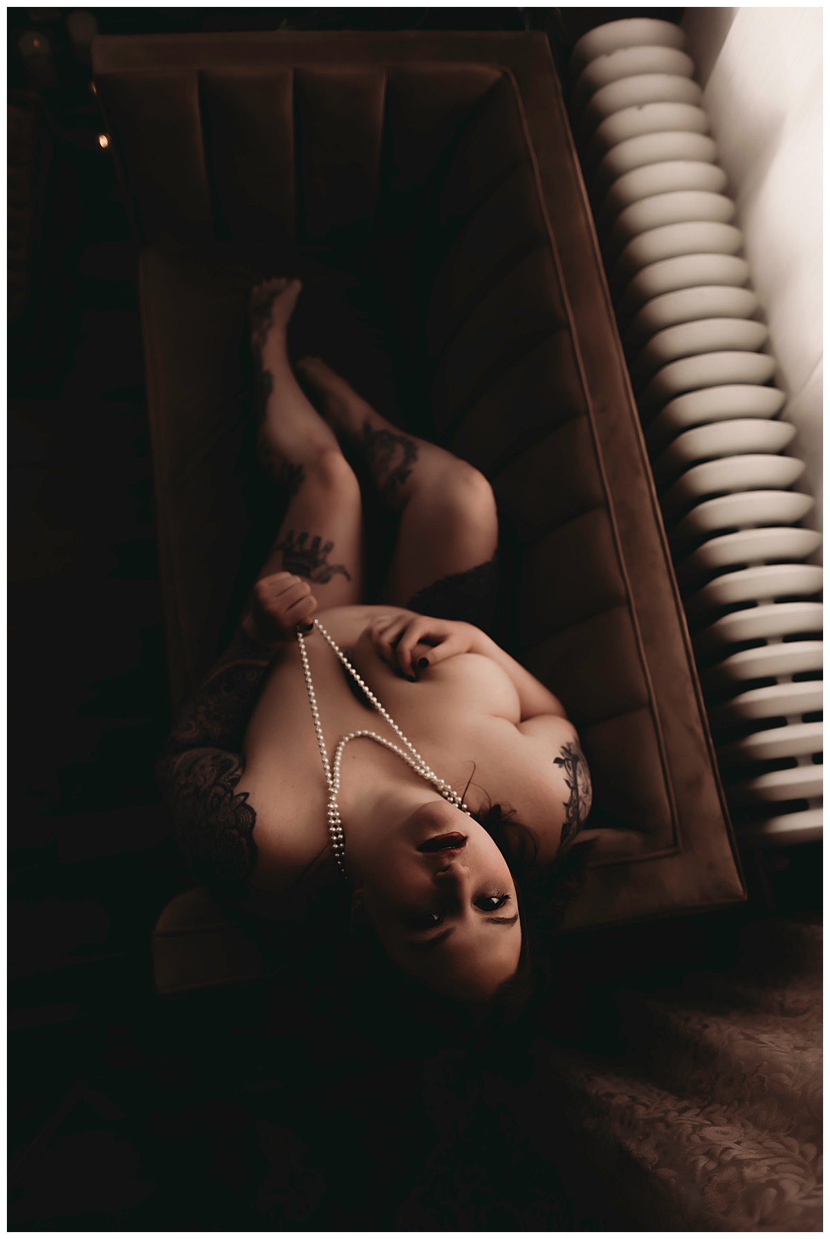 Brunette holds pearls while laying on couch for Minneapolis Boudoir Photographer