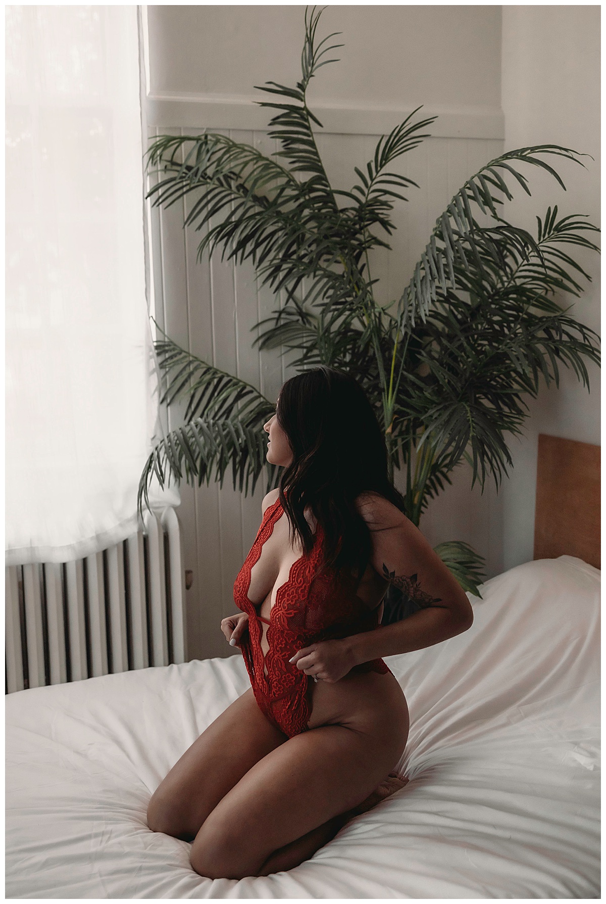 Woman sits on bed in Red Lace Lingerie