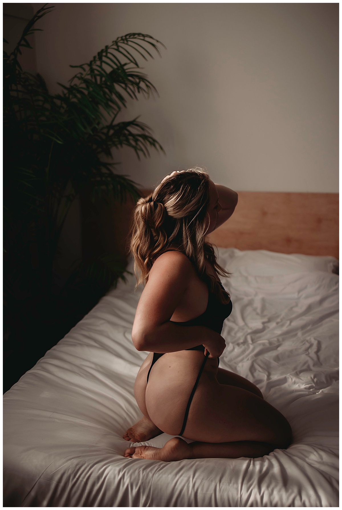 Woman kneels on bed in black lingerie for Boudoir Photography Minnesota